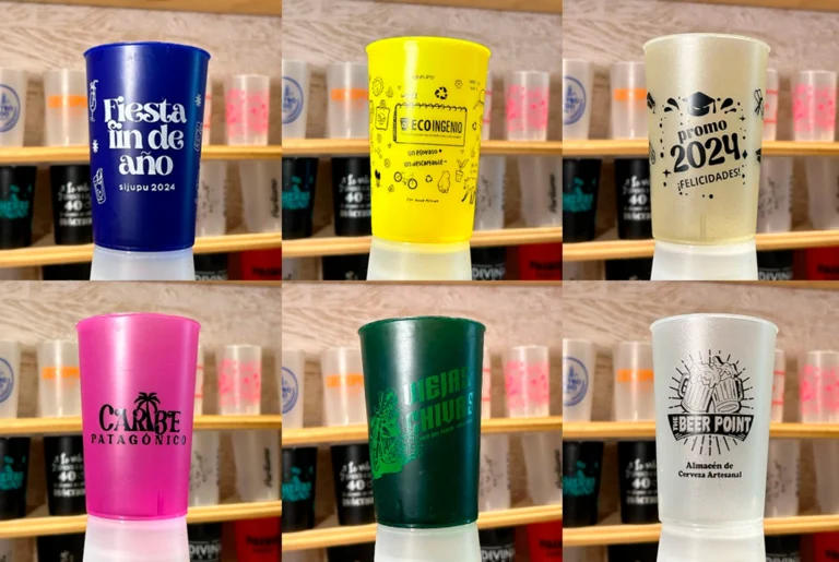 Vasos reutilizables personalizados con logos para eventos y marcas, sobre fondo de estantería de madera